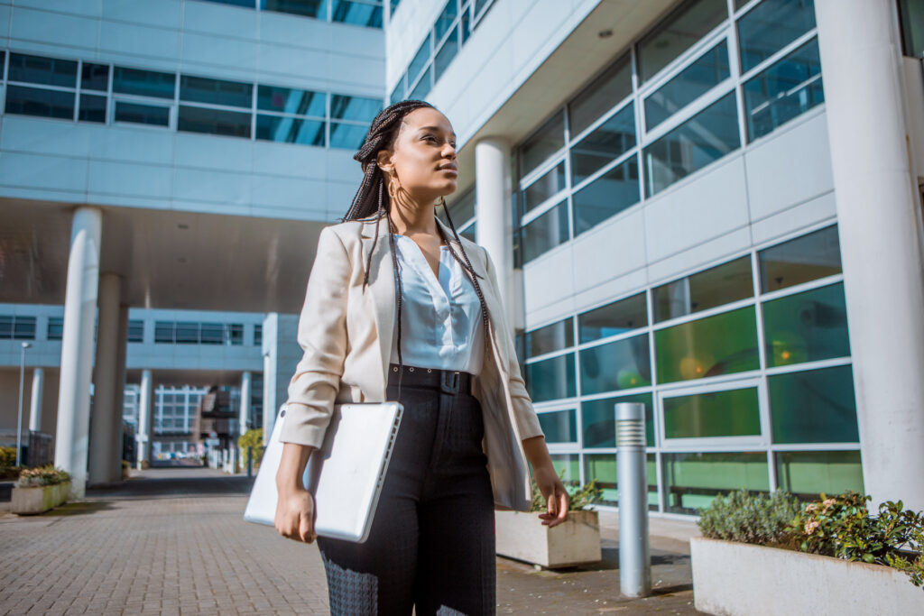 A black female professional business woman outdoors on an office complex in the Spring daytime for article on masters in healthcare administration jobs