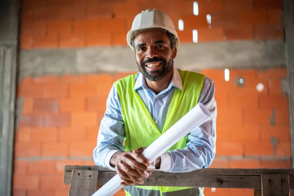 Man standing with plans showing construction management degree jobs
