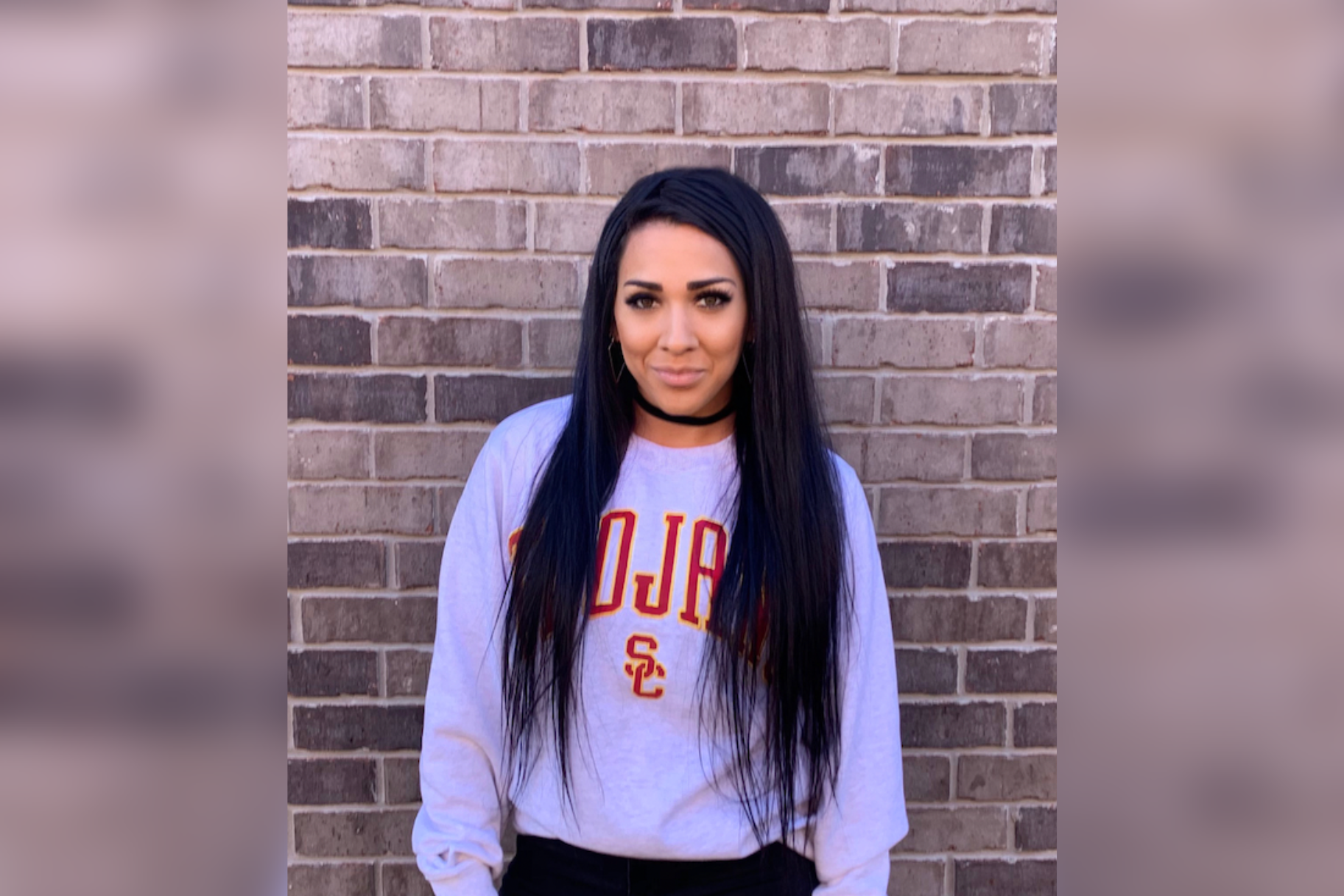 Veronica Frazier Online MPA USC Price Student stands against brick wall in USC Trojans sweatshirt