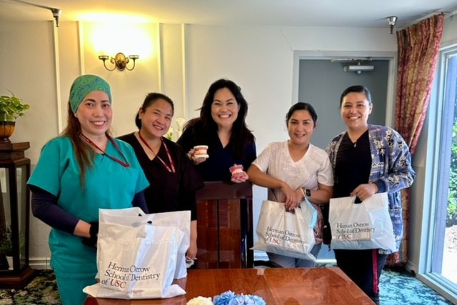 Maya Fulcher with care home employees holding bags of donations after her capstone project.