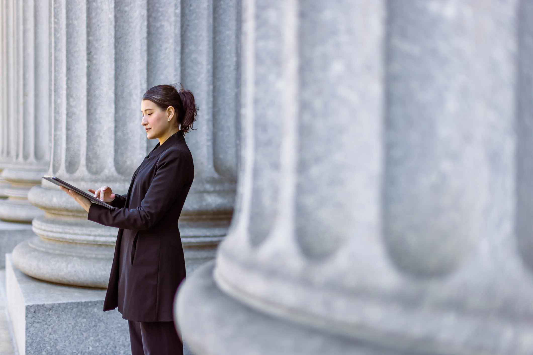 Read about: A woman in a tailored black suit stands at the base of large stone columns and looks at a tablet. Here's how displaced federal employees can transition to jobs in the private sector.
